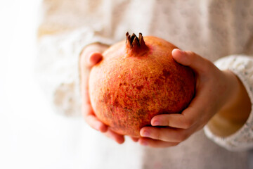Little girl holding a pomegranate. Symbol of the Jewish New Year. Rosh ha Shana. Healthy organic sweet fruits. 