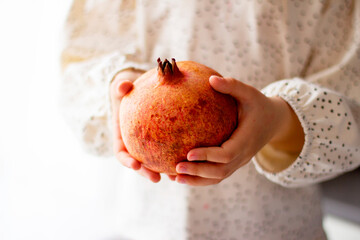 Little girl holding a pomegranate. Symbol of the Jewish New Year. Rosh ha Shana. Healthy organic sweet fruits. 