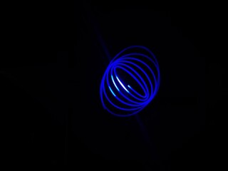 Closeup of Neon blue Spirograph geometric abstract pattern flowing in a isolated black background . Made using Long exposure technique, Light painting. Pendulum pattern. © sanju's view