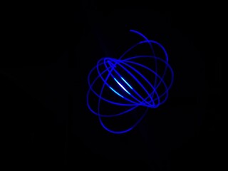Closeup of Neon blue Spirograph geometric abstract pattern flowing in a isolated black background . Made using Long exposure technique, Light painting. Pendulum pattern. © sanju's view