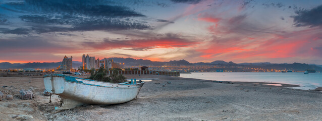 Scenic panoramic view with lonely old fishing boat anchored on a beach of the Red Sea in Eilat -...