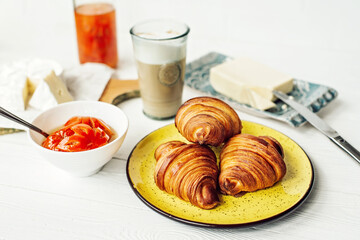 Breakfast with a fresh croissant and a cup of aromatic coffee latte, tangerine jam, butter and brie cheese. Healthy breakfast.
