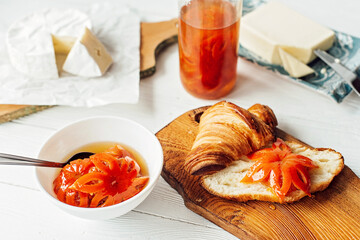 Breakfast with a fresh croissant and a cup of aromatic coffee latte, tangerine jam, butter and brie cheese. Fruit carving. Healthy breakfast.