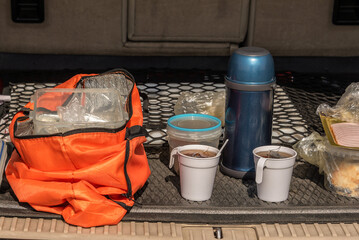 Cups of tea, a thermos, food in the trunk of the car. A snack during a car travel. Stopping for a rest and snack. Pitstop.