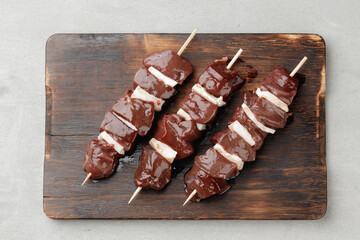 Raw beef liver on skewers on board
