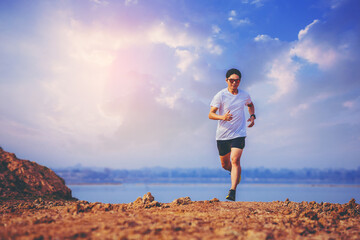Young man runner running trail on sunrise lakeside. Healthy and lifestyle concept