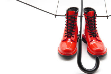 Red rubber boots close-up. A pair of women's ankle boots under a transparent umbrella-cane on a white background. Autumn style concept, sales and discounts, comfortable clothing. Copyspace.