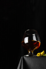 Cognac, rum, whiskey or other alcoholic drink in a glass, olives on a black background. Strong alcohol.