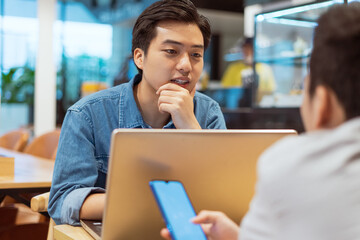The Asian man talking to his friend