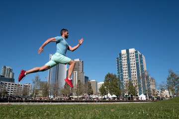 Fototapeta na wymiar Full length of healthy man running and jogging outdoors. Male model in sportswear exercising outdoors in city park. Urban sport concept.