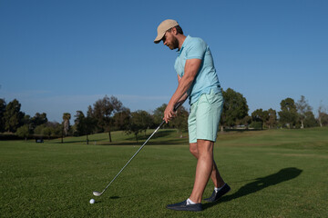 Fototapeta premium Golf player playing golf on sunny day. Professional golfer taking shot on golf course.