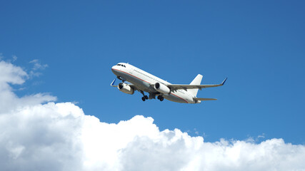 Fototapeta na wymiar Zoom photo of passenger airplane taking off reaching altitude above clouds in deep blue sky