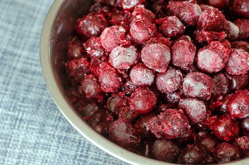 Frozen cherries in a metal bowl on the table.