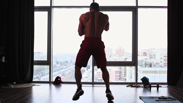 Sports training in studio with panoramic windows - muscular man performing shadowboxing