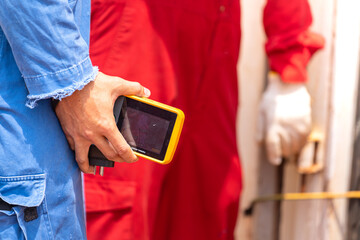 Close-up at electrician is holding a thermal imager camera, device to scanning heat and temperture...