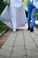 the bride in a white wedding dress and the groom in a blue cat suit are walking along the road