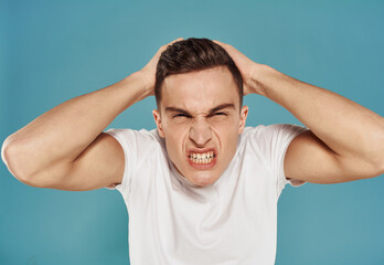 Angry man in white t-shirt gesture with hands displeasure blue background