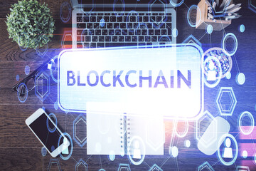 Blockchain theme hologram drawings over computer on the desktop background. Top view. Double exposure.