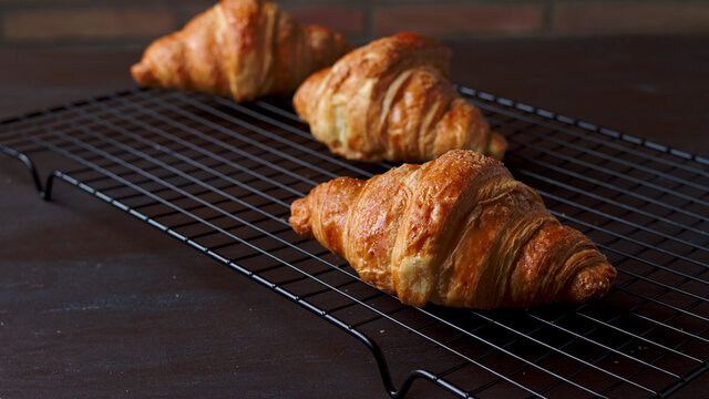 croissant reci&eacute;n horneados enfiandose en una rejilla met&aacute;lica