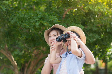 Asian mother and son using binoculars  outdoors in sunny summer day