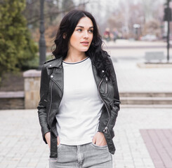 Fototapeta premium Beautiful brunette woman with curly hair posing on the street while walking