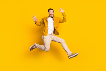 Fototapeta na wymiar Full length photo of funny impressed young gentleman dressed casual outfit smiling jumping high isolated yellow color background