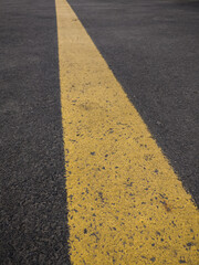 Fototapeta premium A yellow line as a boundary for bicycle road with soft focus. Asphalt Road texture background. Wallpaper, banner