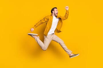 Fototapeta na wymiar Full length photo of hurrying funny gentleman dressed casual outfit smiling jumping high running isolated yellow color background