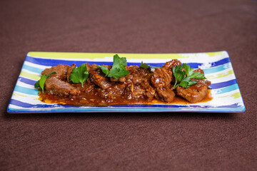 beef with sauce with herbs on a striped plate