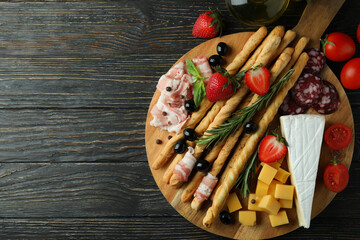Board with grissini and snacks on wooden background