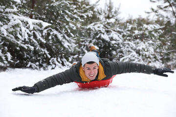 Fototapeta na wymiar Happy man sledding outdoors on winter day. Christmas vacation