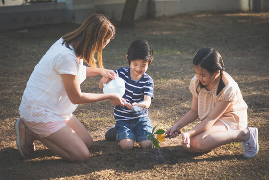 Cute Asian children and mother planting young tree on the black soil,Earth day concept