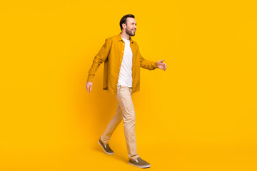 Fototapeta na wymiar Full length photo of adorable pretty gentleman dressed casual outfit walking looking empty space isolated yellow color background