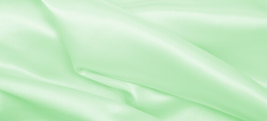 Smooth elegant green silk or satin luxury cloth texture as abstract background. Luxurious background design