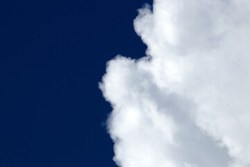 Fototapeta na wymiar White fluffy clouds on a dark blue sky - cloudscape, overcast - cloudscape background