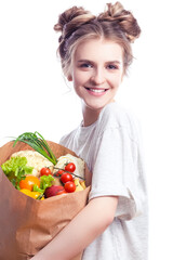 Healthy Eating Ideas. Portrait of Young Caucasian Girl With Eco Paper Bag Filled With Multiple Vegetables and Groceries Posing With Smile Against White Background.