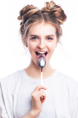 Positive Caucasian Blond Girl Posing in White T-Shirt With Shiny Metal Spoon in Front of The Mouth Against Pure White Background.