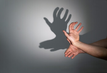 A man's hands folded in a gesture giving shadow in the form of a moose on a light wall.
