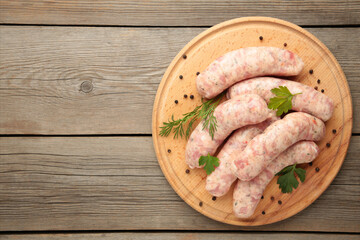 Raw sausage on cutting board on grey wooden background. Top view