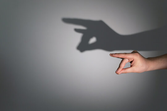 A man's hands folded in a gesture giving a shadow in the form of a roe deer head on a light wall.  The concept of shadow theater.