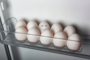Closeup of a smiling egg in a roe of white eggs