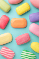 Different soaps in different soap dishes. A lot of solid soap for hygiene and cleanliness. Colorful soap and remnants are scattered on blue background.