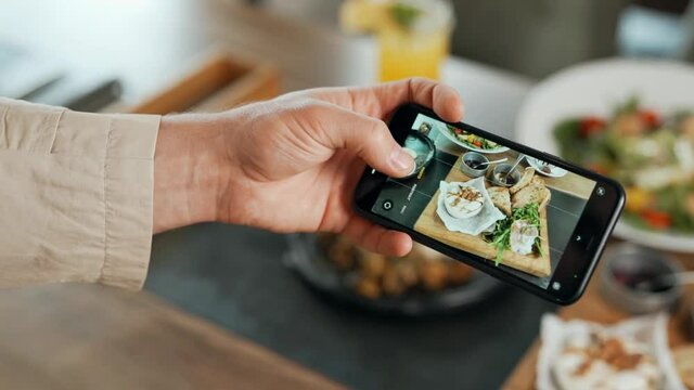 Close-up of male hand taking photo on smartphone food on table
