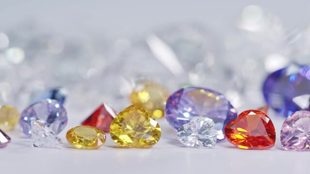 A big pile of colorful gemstones  are placed on white floor with white diamonds background.

