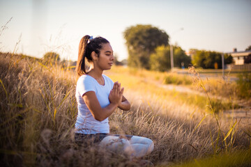 African young woman in nature sitting in yoga position.