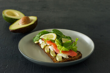 Sandwich with smoked salmon soft cheese, lattice and avocado. Concept for a tasty and healthy meal. Food on a plate.