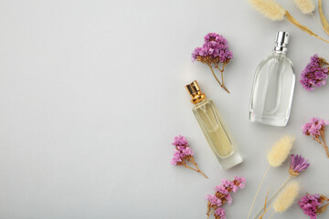 Obraz na płótnie Canvas Bottle of perfume with flowers on grey background