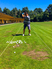 Obraz premium Man training Golf swing on driving range in a sunny day in Switzerland.
