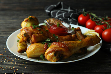Concept of delicious eating with plate of roast chicken drumsticks on wooden background