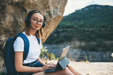 happy young girl with glasses and backpack enjoying summer holidays listen music in headphones and...